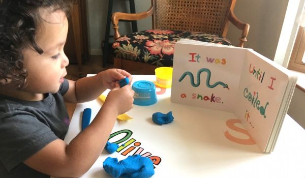 Child playing with clay while reading