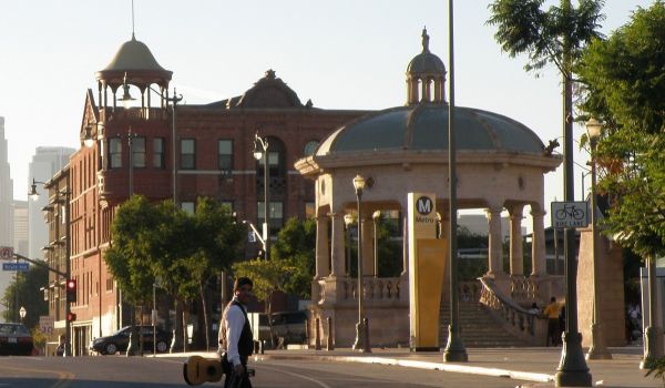 Mariachi member crossing street with guitar near Mariachi Plaza