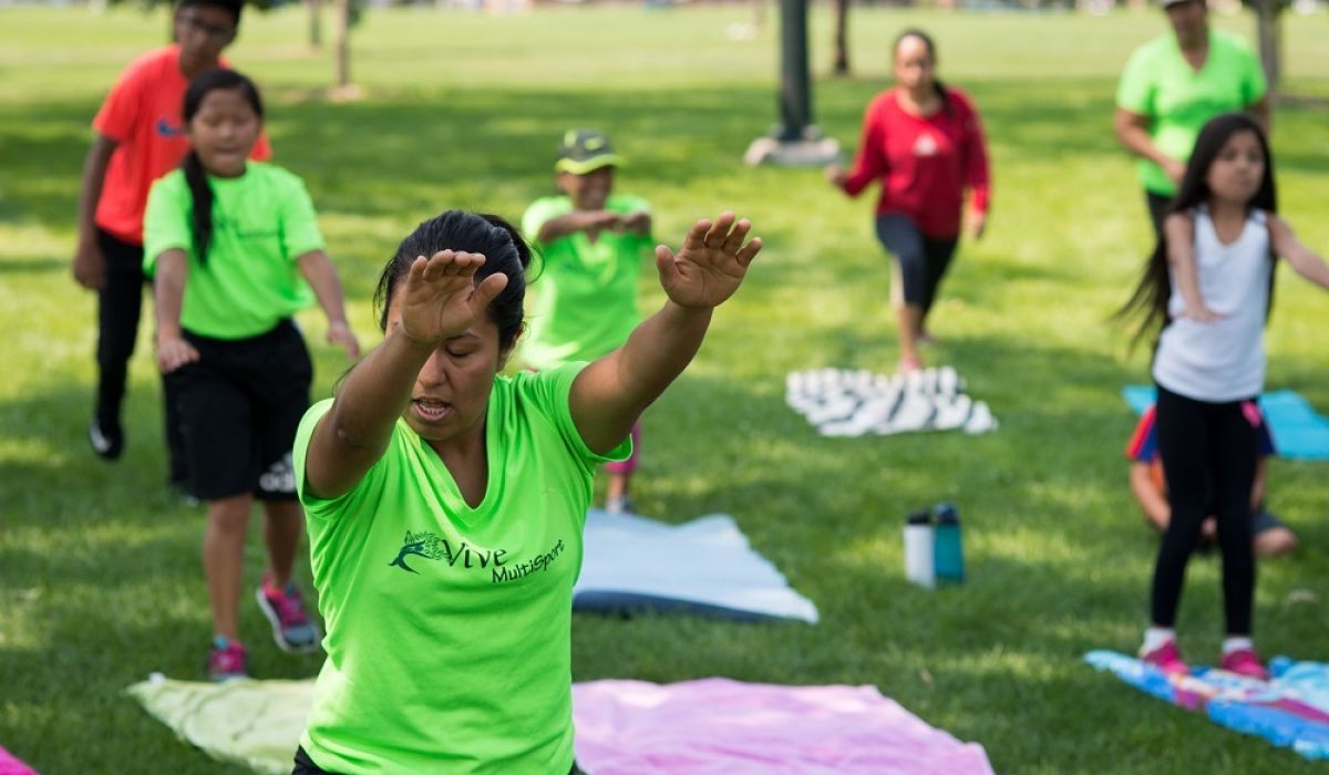 A group of people of all ages practicing yoga outdoors