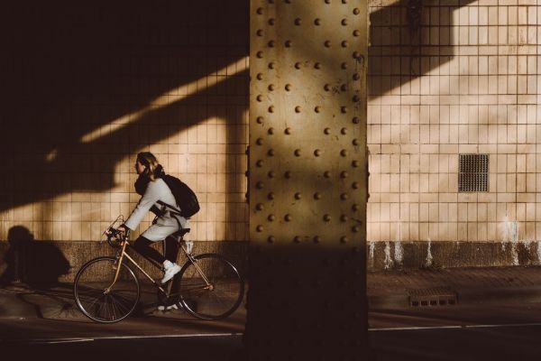 Person on a retro bike riding from the sunlight into the shadows.