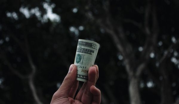 Person holds a roll of $20 bills