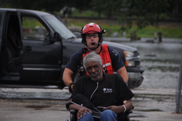 A pararescueman assigned to the New York Air National Guard pushes an elderly man toward the HH-60 Pave Hawk helicopter in Houston area, August 30, 2017.