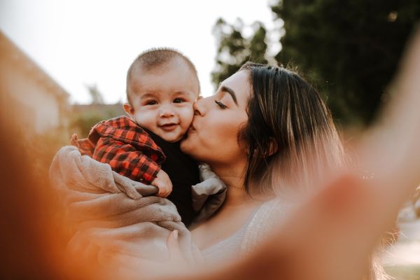 Person kisses baby on cheek while taking picture